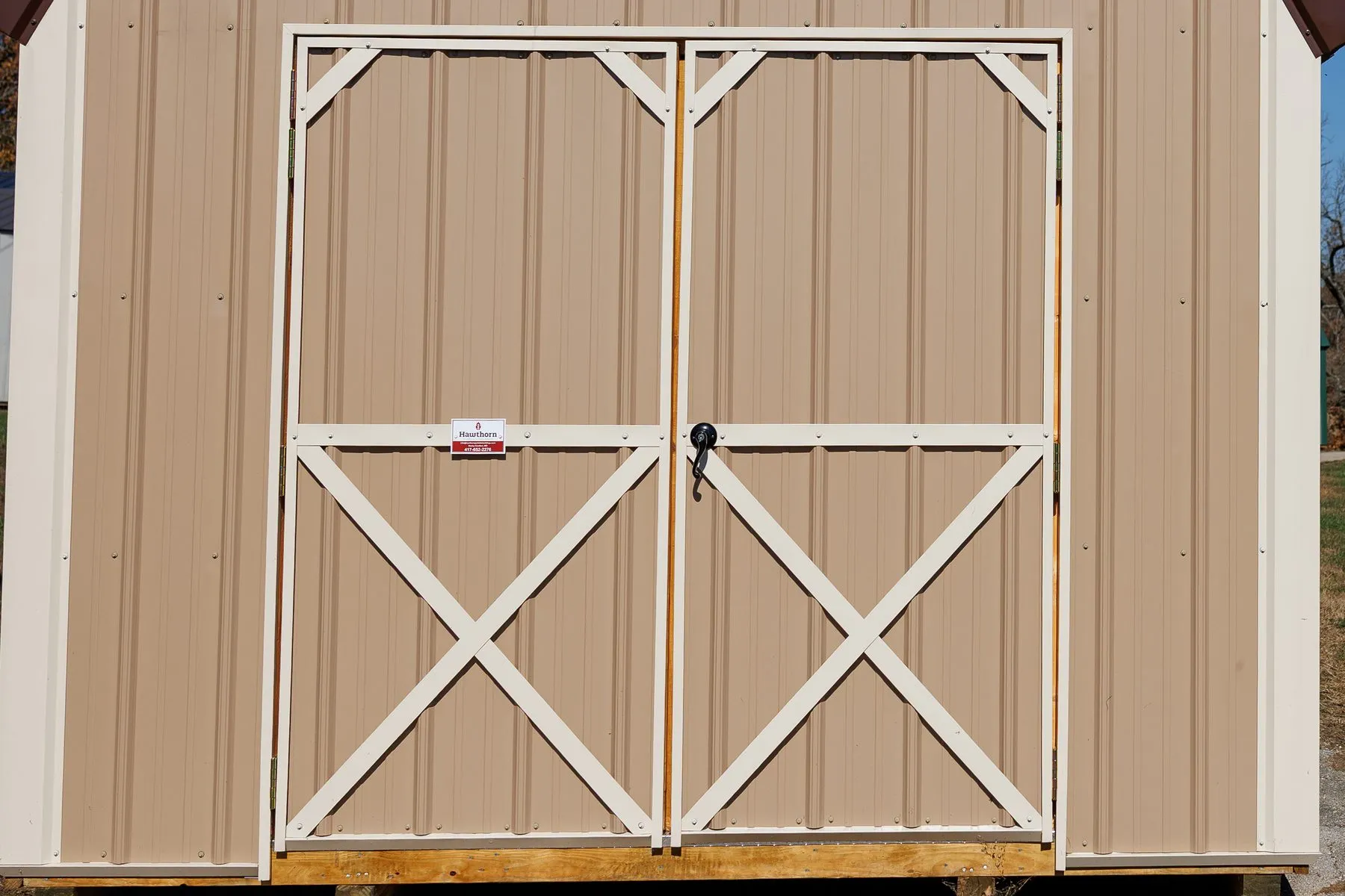 Double doors with cream X-trim and a locking handle on a tan Hawthorn barn