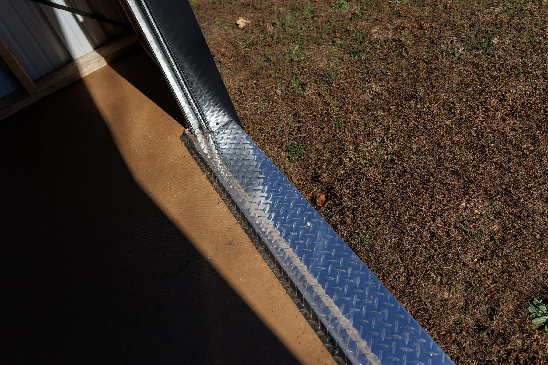 The aluminum diamond-plate threshold at a Hawthorn doorway
