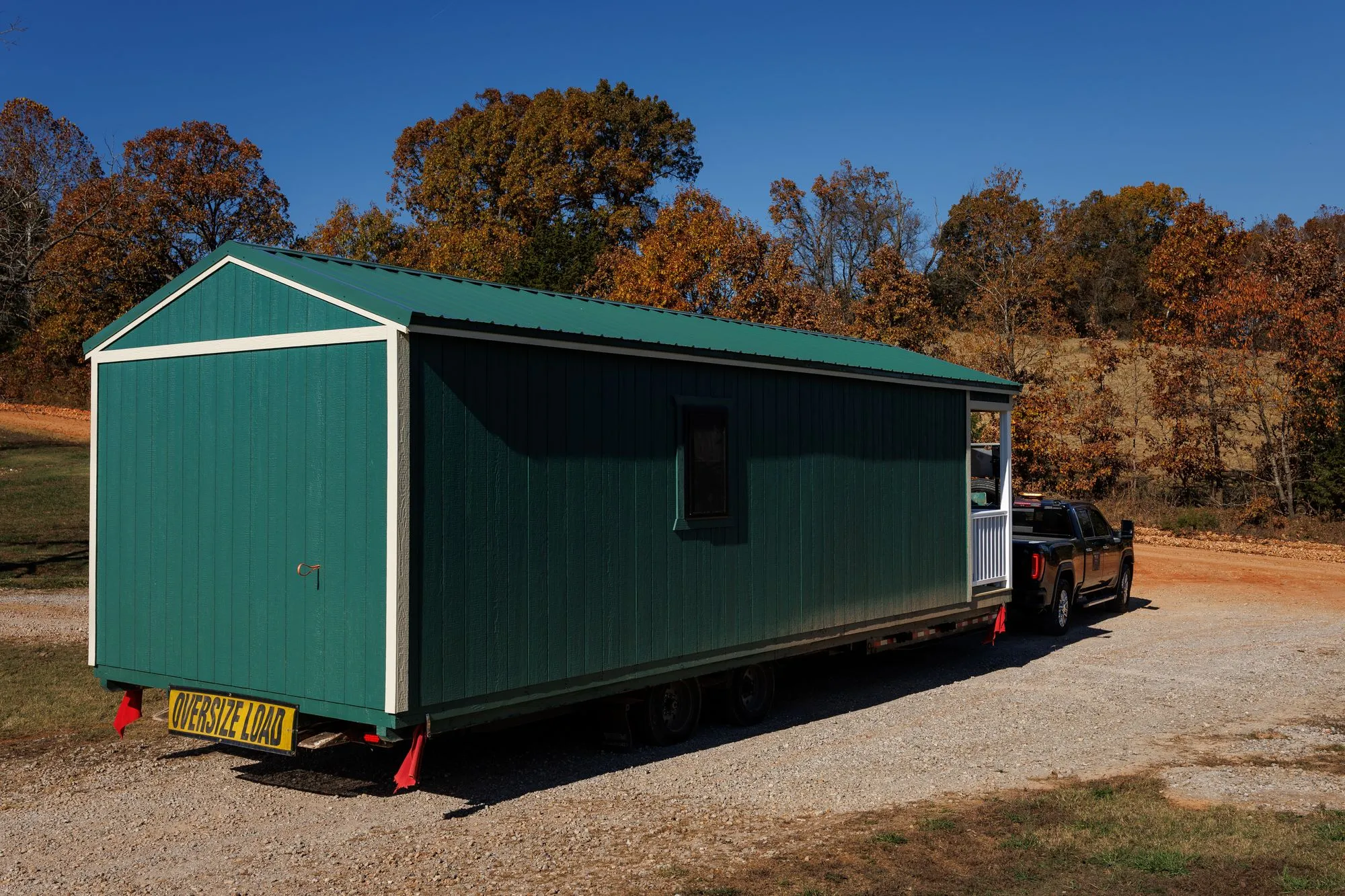 A long green Hawthorn building on a delivery trailer leaving the lot