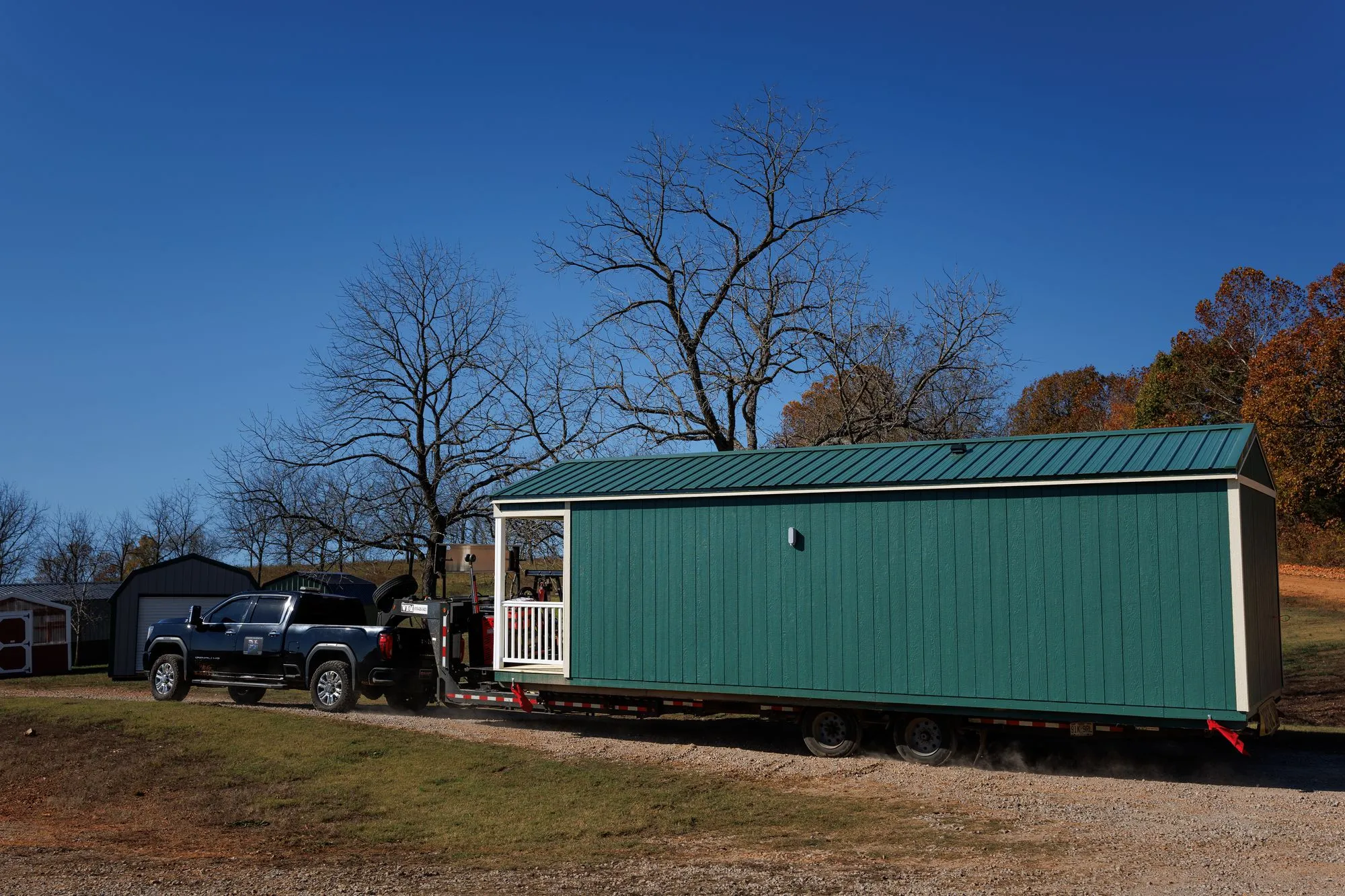 A pickup truck towing a long green Hawthorn building past the lot