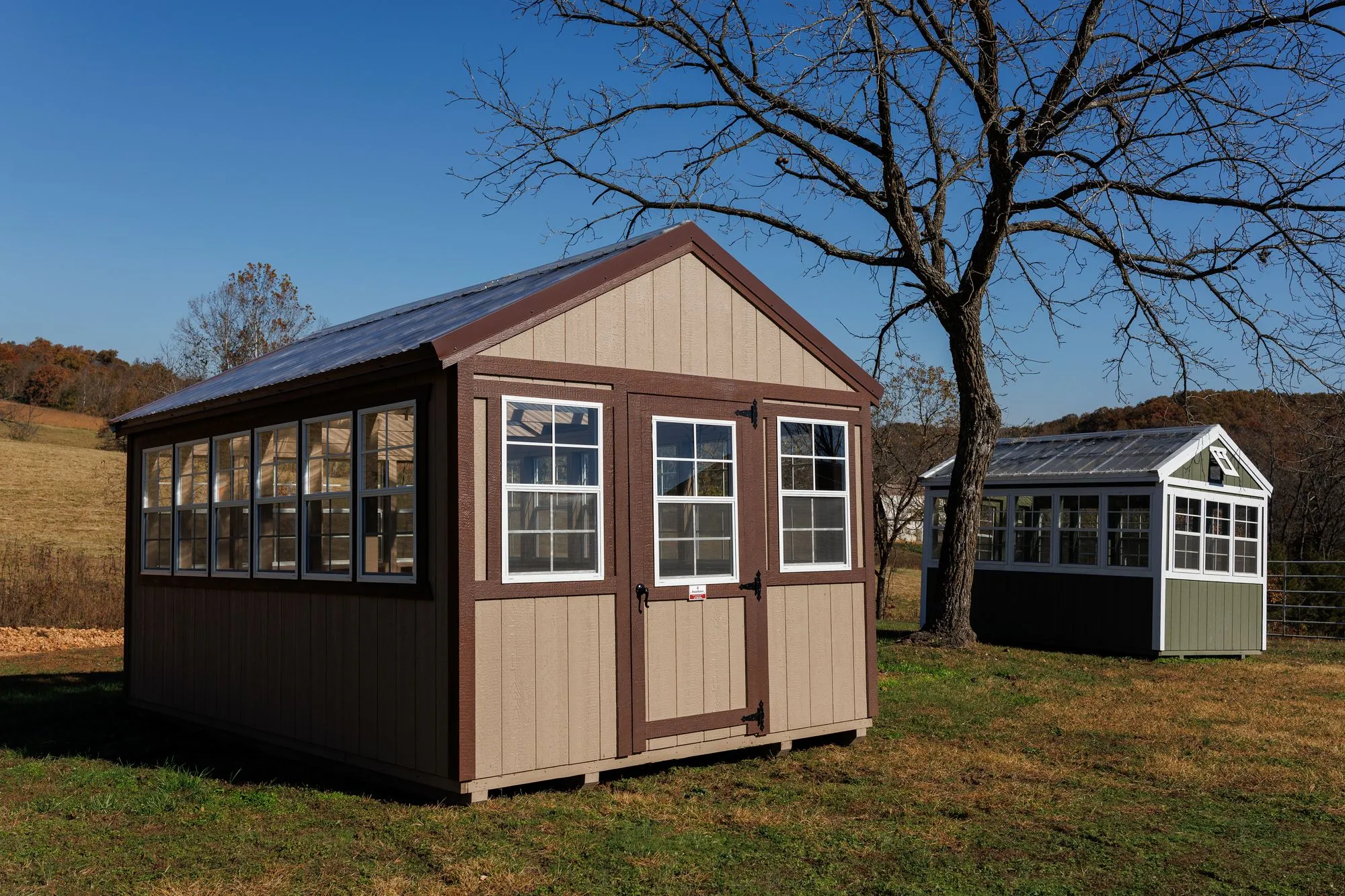 Greenhouse with tan siding with brown trim and a clear corrugated roof, on the Hawthorn lot in Rocky Comfort, Missouri