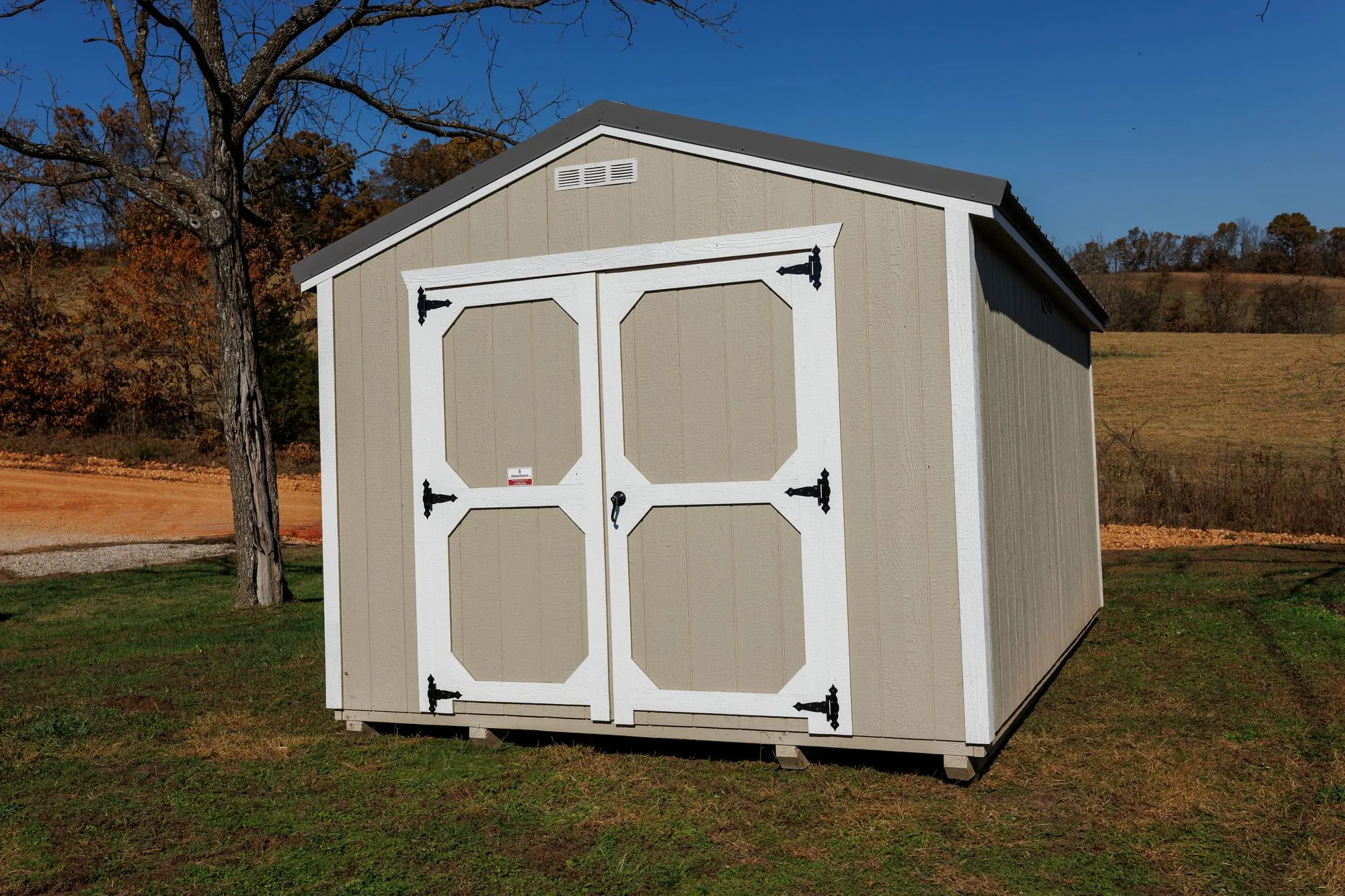 Utility Shed with taupe siding, white trim, charcoal roof, white octagon-panel doors, on the Hawthorn lot in Rocky Comfort, Missouri