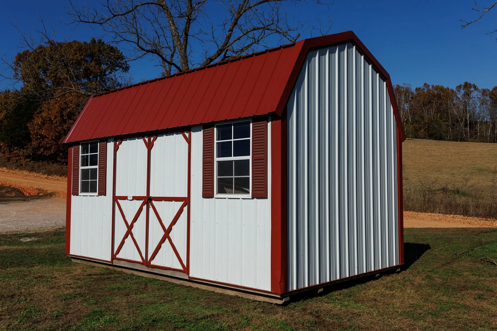 Lofted Garden Barn with white metal siding, red trim and roof, on the Hawthorn lot in Rocky Comfort, Missouri