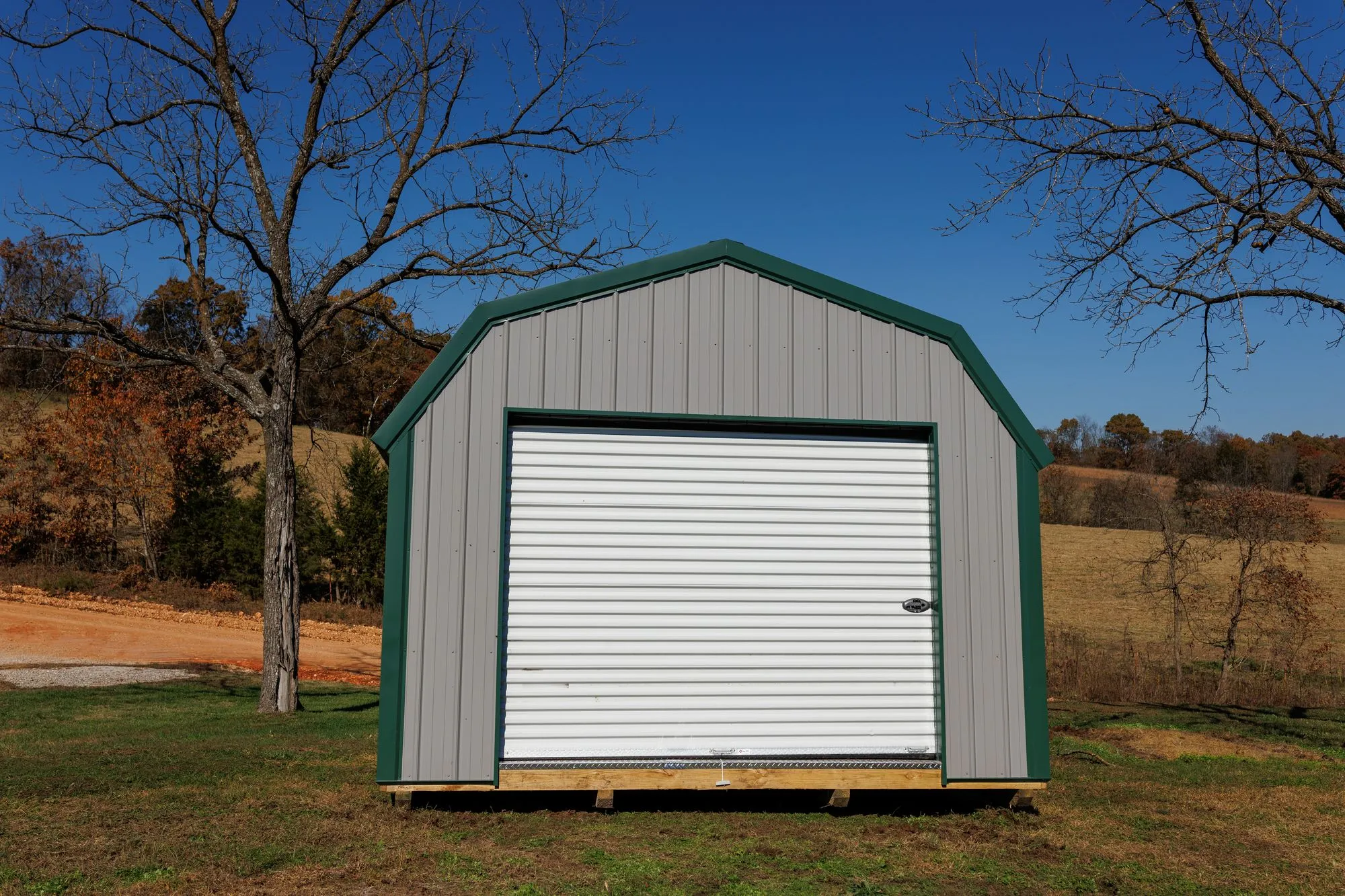 Lofted Garage with gray metal siding with green trim and roof, on the Hawthorn lot in Rocky Comfort, Missouri