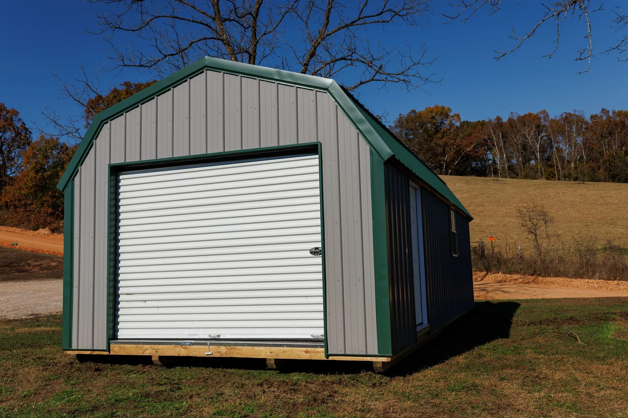 Lofted Garage with gray metal siding with green trim and roof, on the Hawthorn lot in Rocky Comfort, Missouri