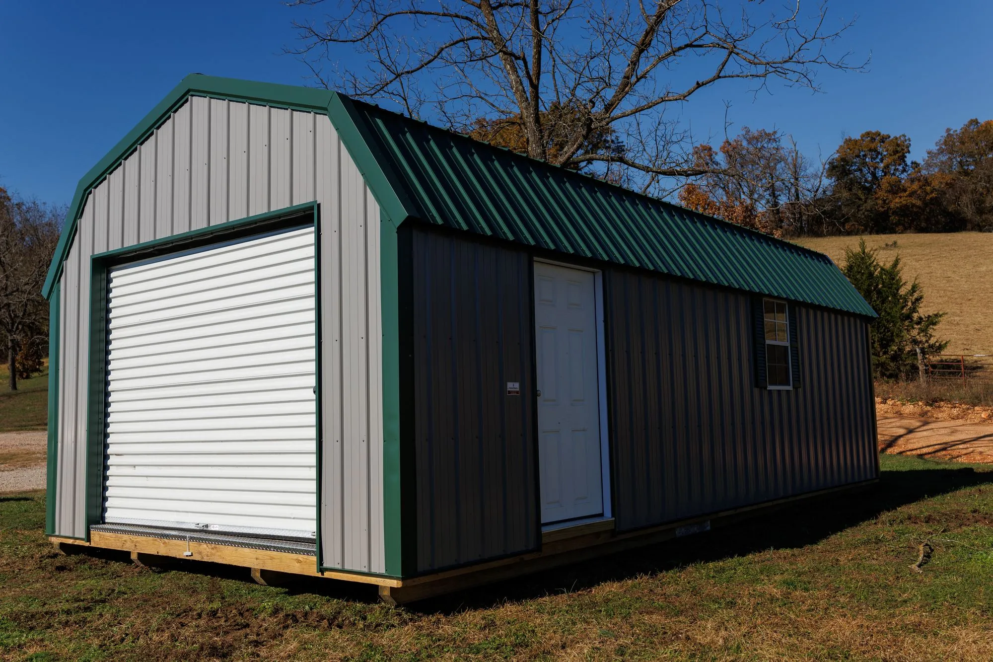 Lofted Garage with gray metal siding with green trim and roof, on the Hawthorn lot in Rocky Comfort, Missouri