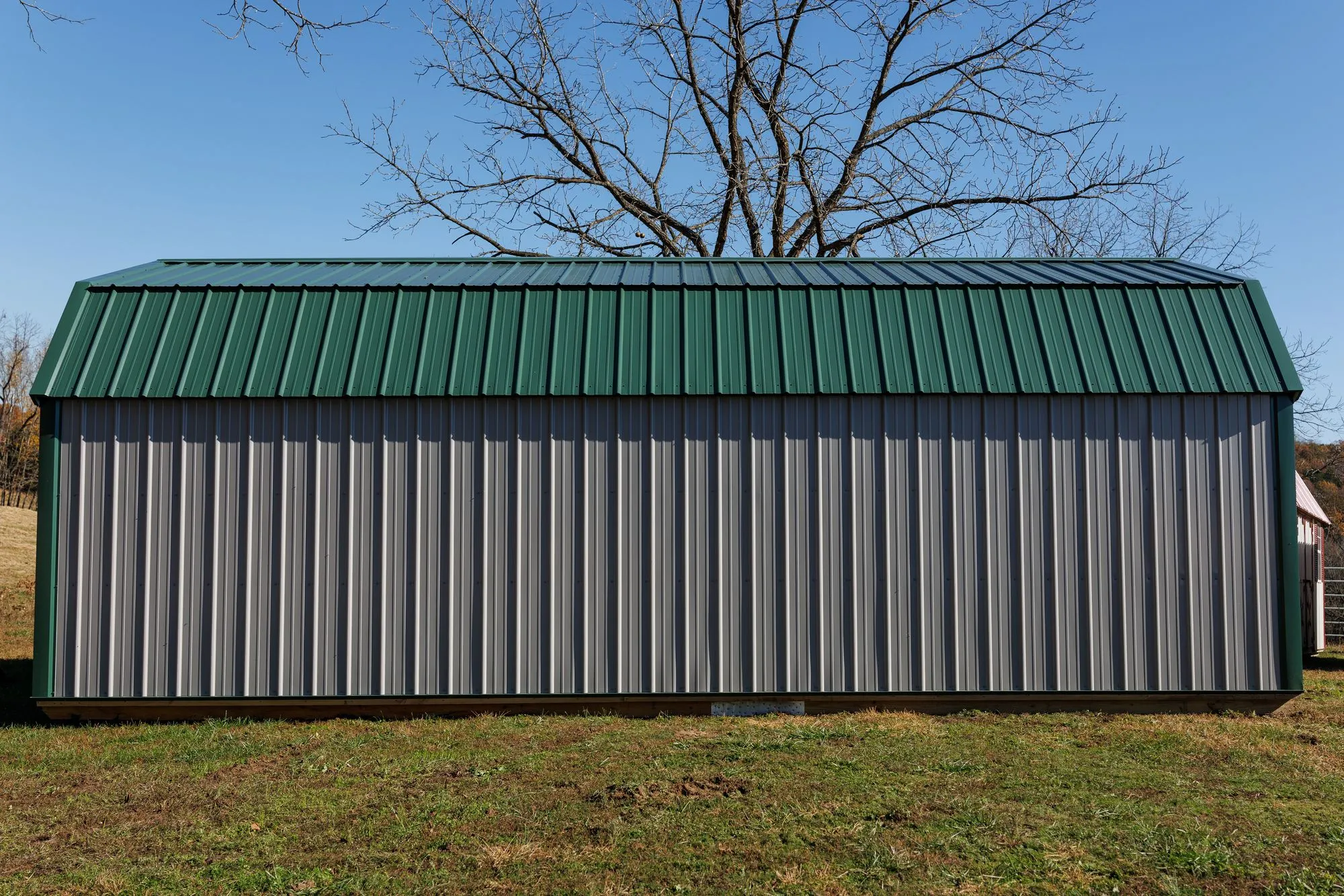 Lofted Garage with gray metal siding with green trim and roof, on the Hawthorn lot in Rocky Comfort, Missouri