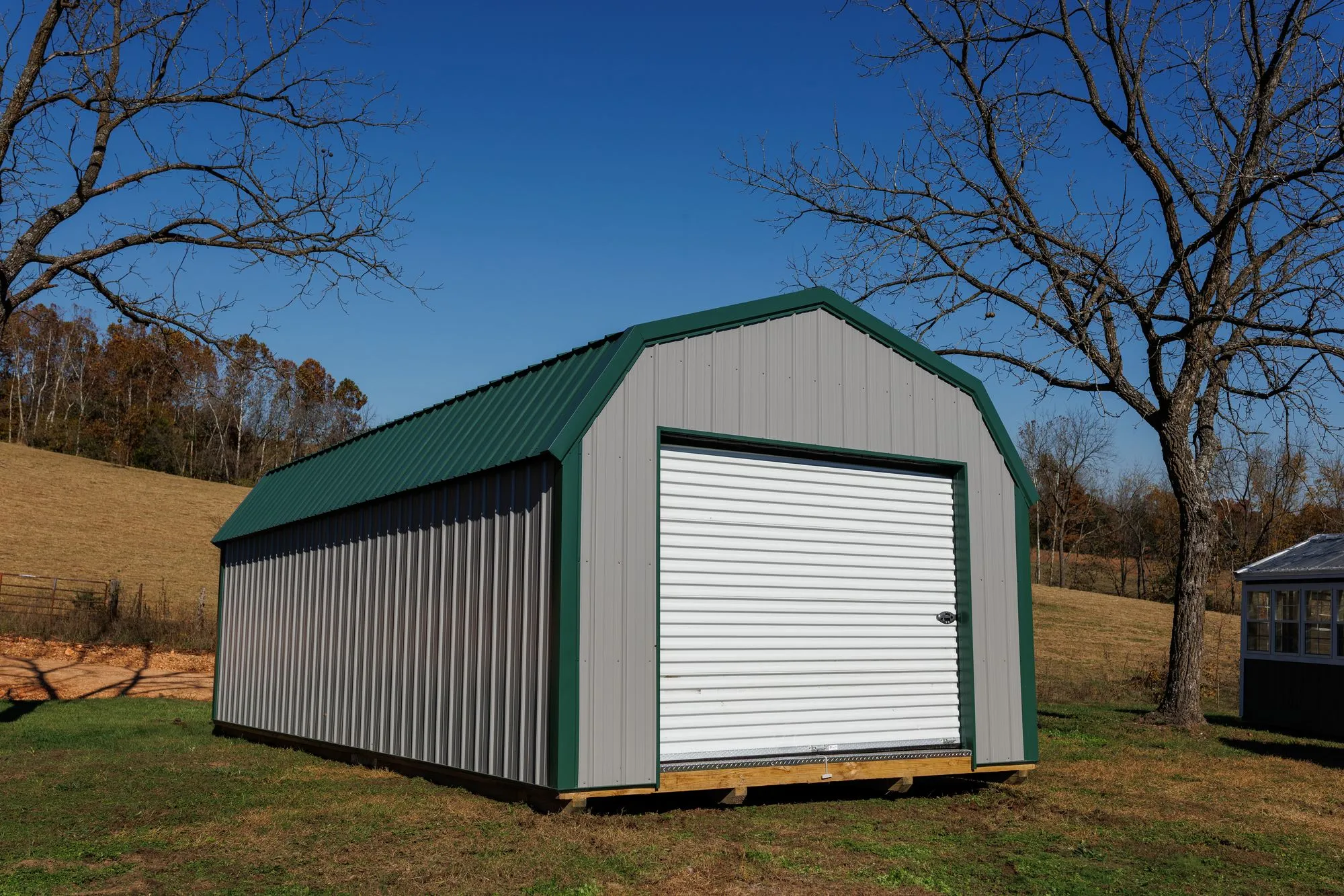 Lofted Garage with gray metal siding with green trim and roof, on the Hawthorn lot in Rocky Comfort, Missouri