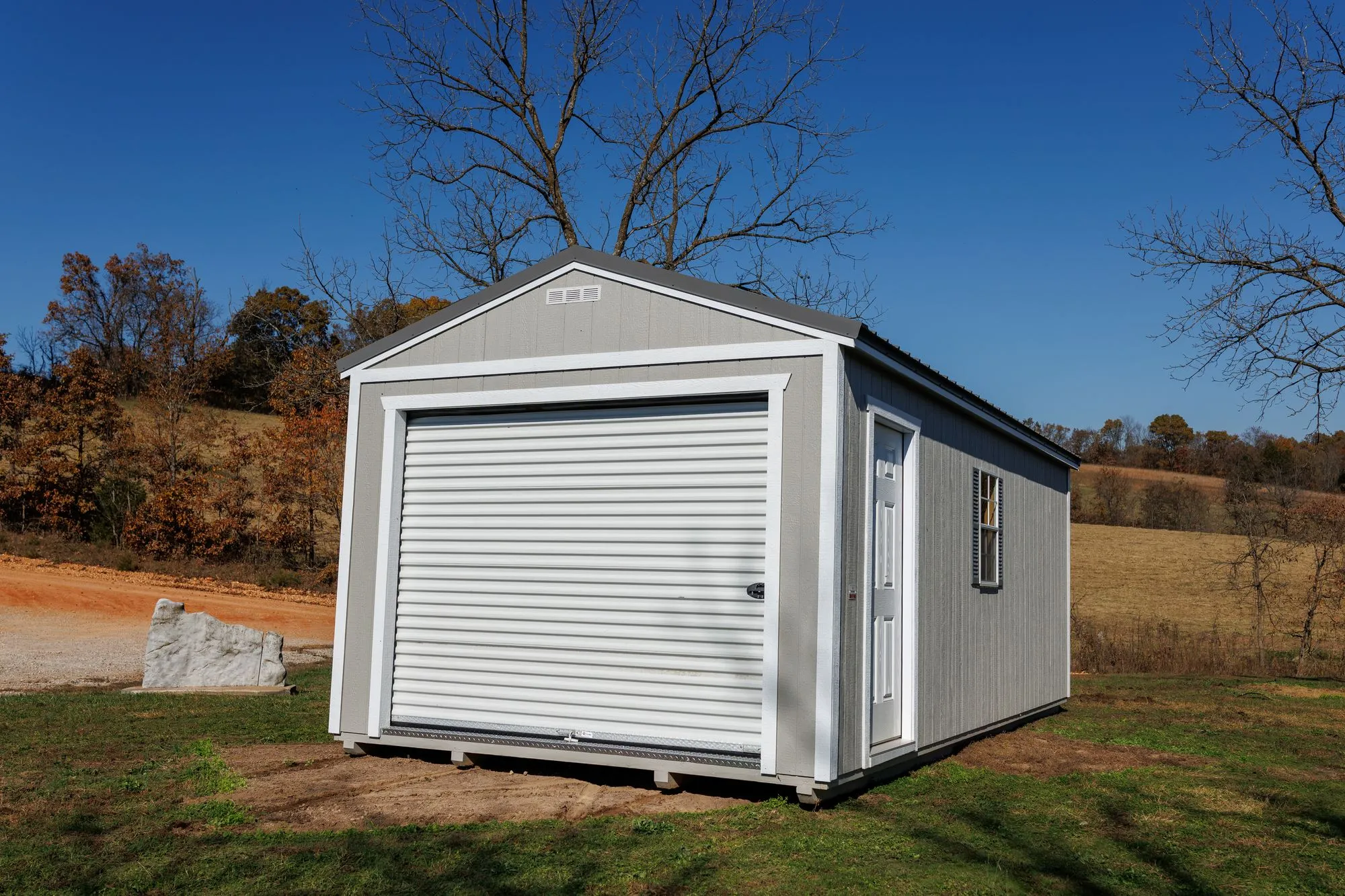 Portable Garage with gray siding, white trim, charcoal roof, on the Hawthorn lot in Rocky Comfort, Missouri