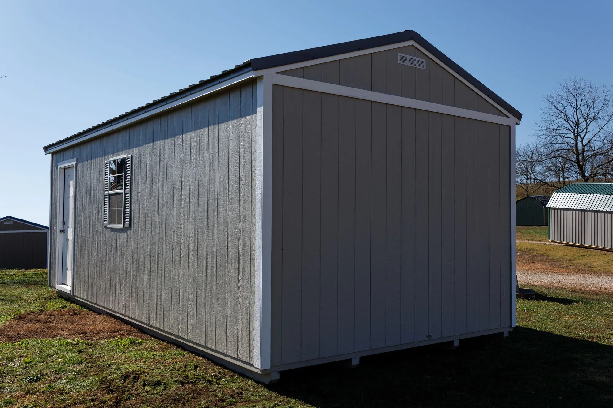 Portable Garage with gray siding, white trim, charcoal roof, on the Hawthorn lot in Rocky Comfort, Missouri