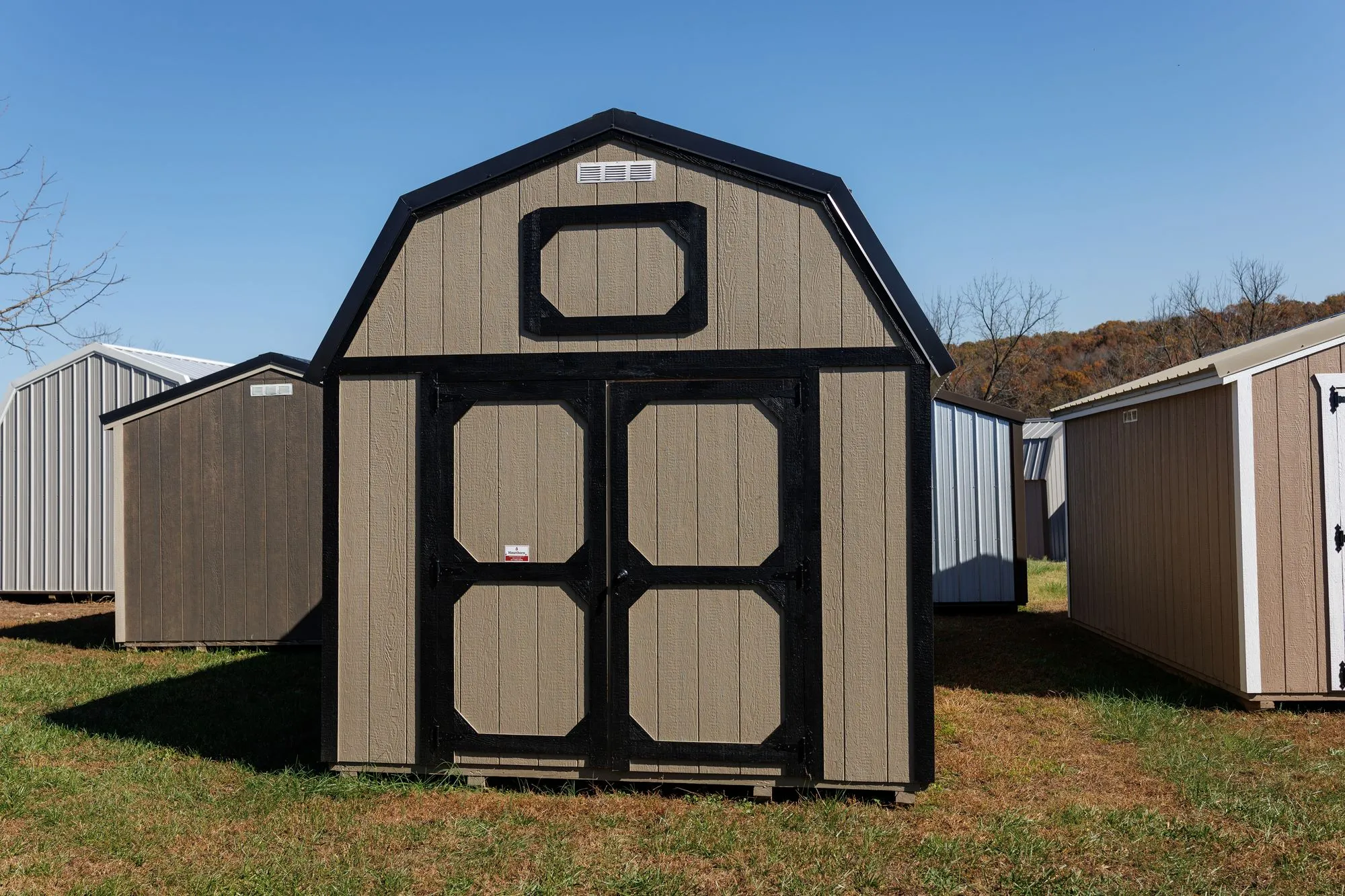 Lofted Barn with tan siding with black trim and roof, octagon-panel doors, on the Hawthorn lot in Rocky Comfort, Missouri