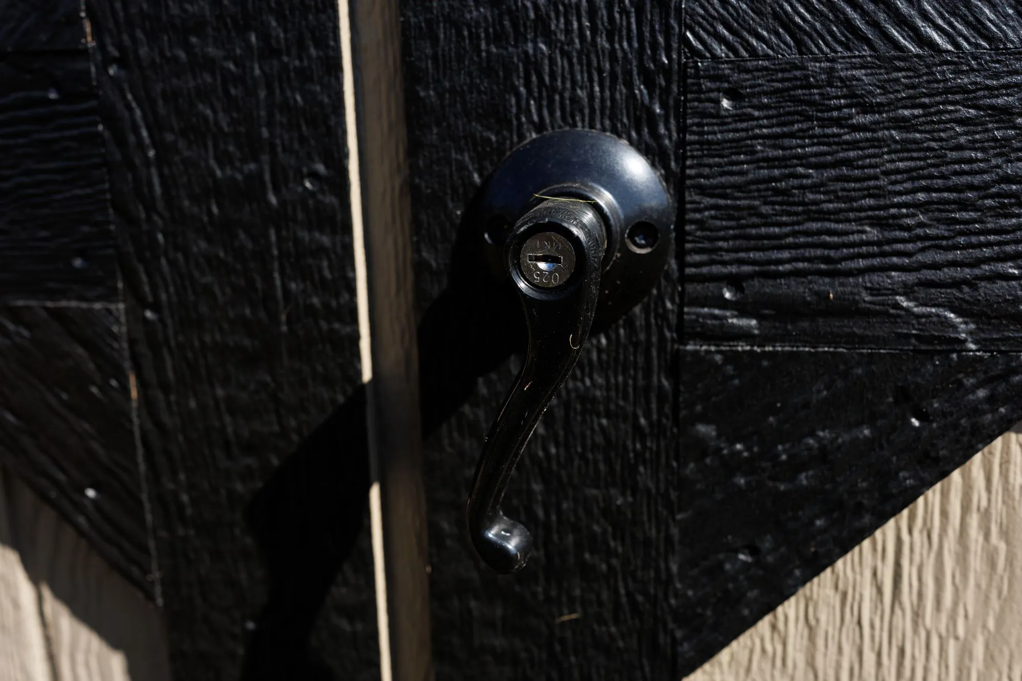 Close-up of a keyed door handle on a black-painted Hawthorn door