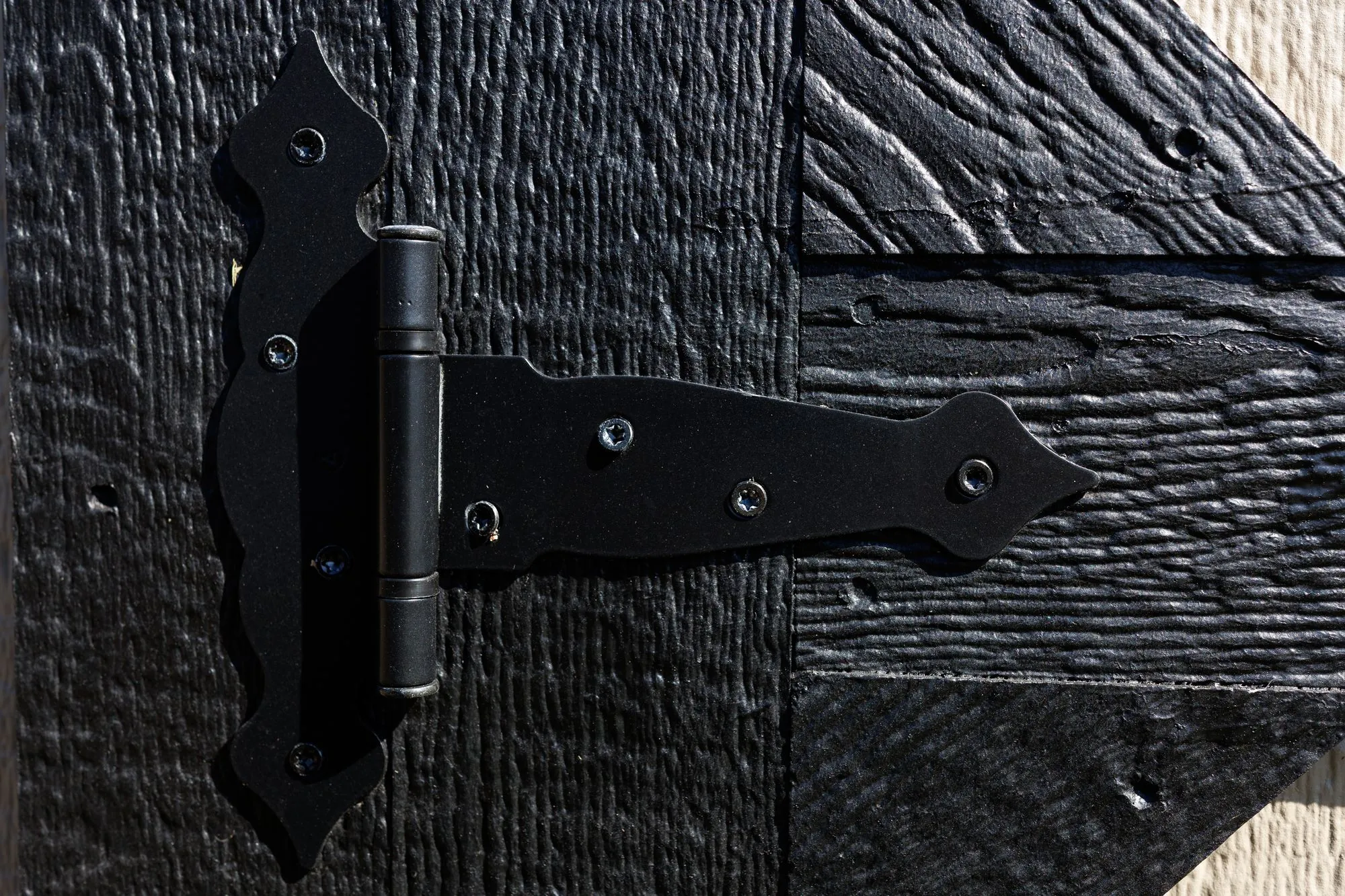 Close-up of a black strap hinge on a painted Hawthorn door