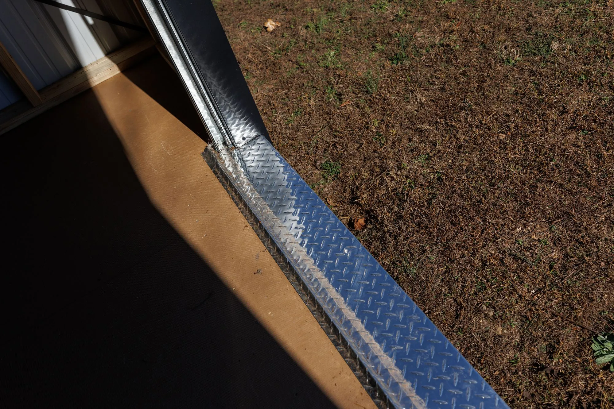 Close-up of the aluminum diamond-plate threshold at a Hawthorn doorway