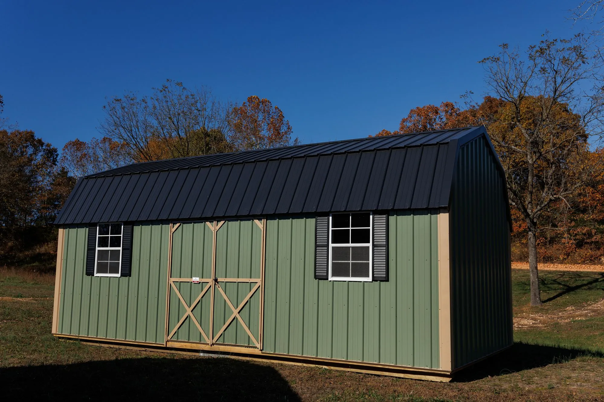 Lofted Garden Barn with sage-green metal siding, tan trim, black roof, on the Hawthorn lot in Rocky Comfort, Missouri