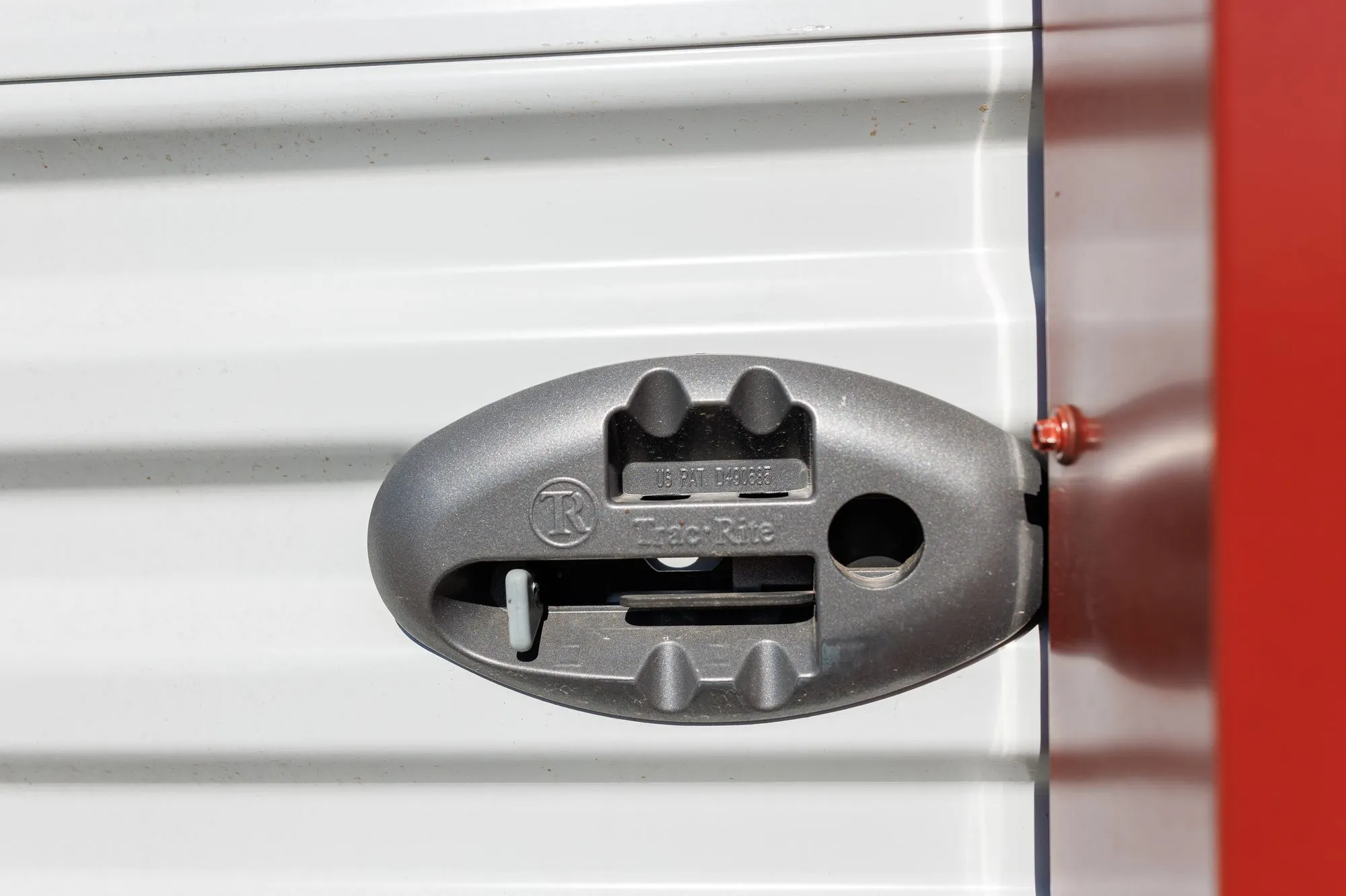 Close-up of the roll-up door latch on a white metal Hawthorn garage with red trim