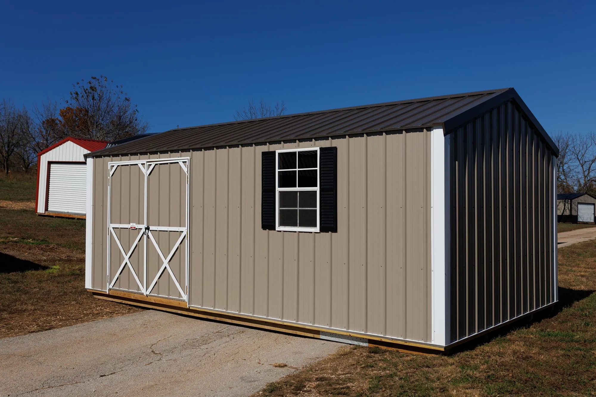 Garden Shed with clay metal siding, white trim, black roof, white X-braced doors, on the Hawthorn lot in Rocky Comfort, Missouri
