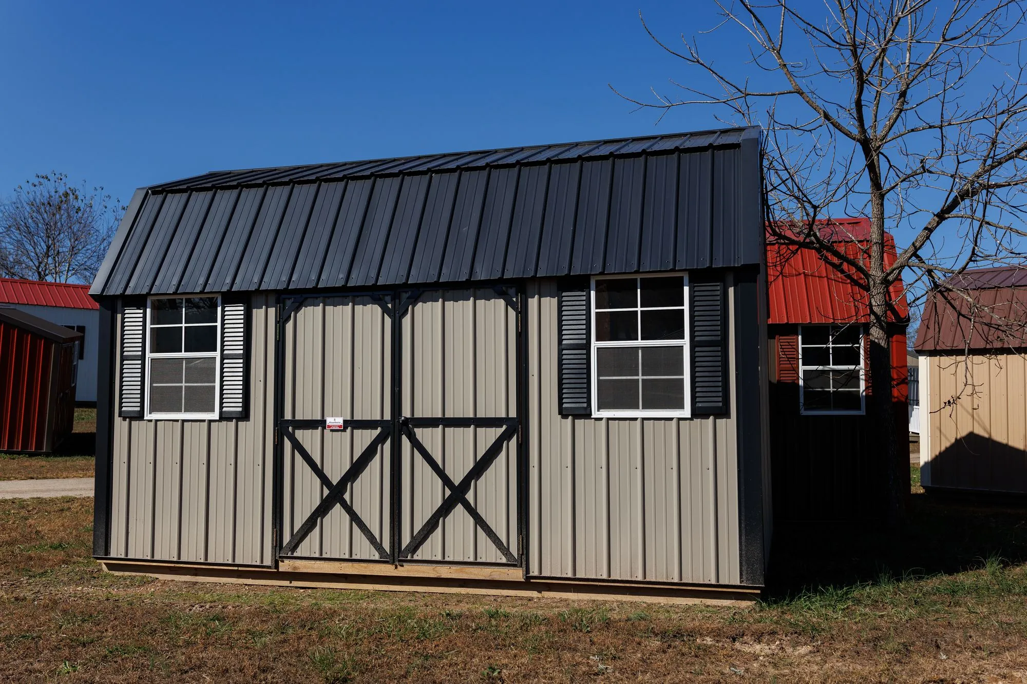 Lofted Garden Barn with clay-colored metal siding, black trim and roof, on the Hawthorn lot in Rocky Comfort, Missouri