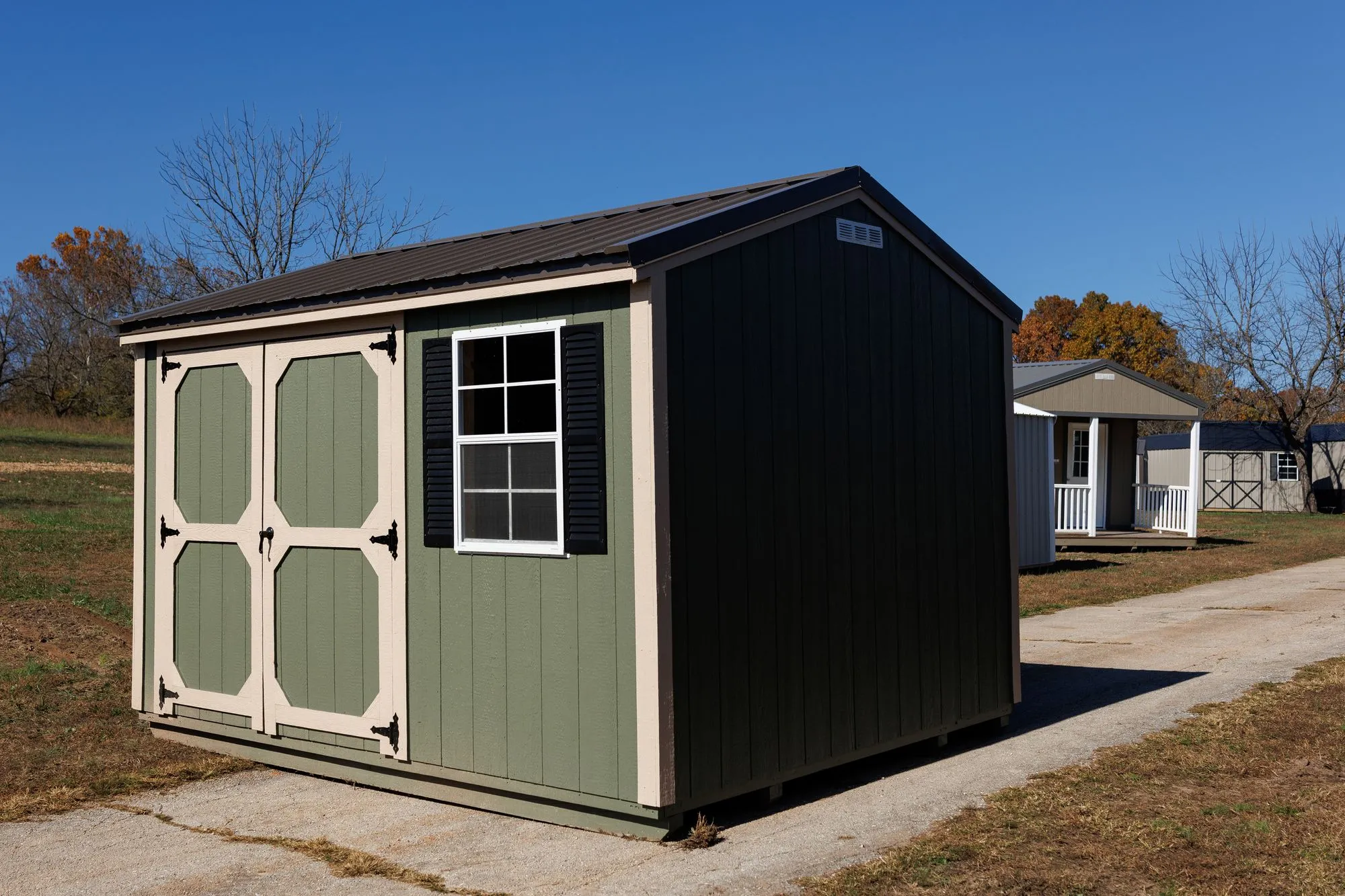 Garden Shed with sage siding, cream trim, black roof, cream-framed doors, on the Hawthorn lot in Rocky Comfort, Missouri