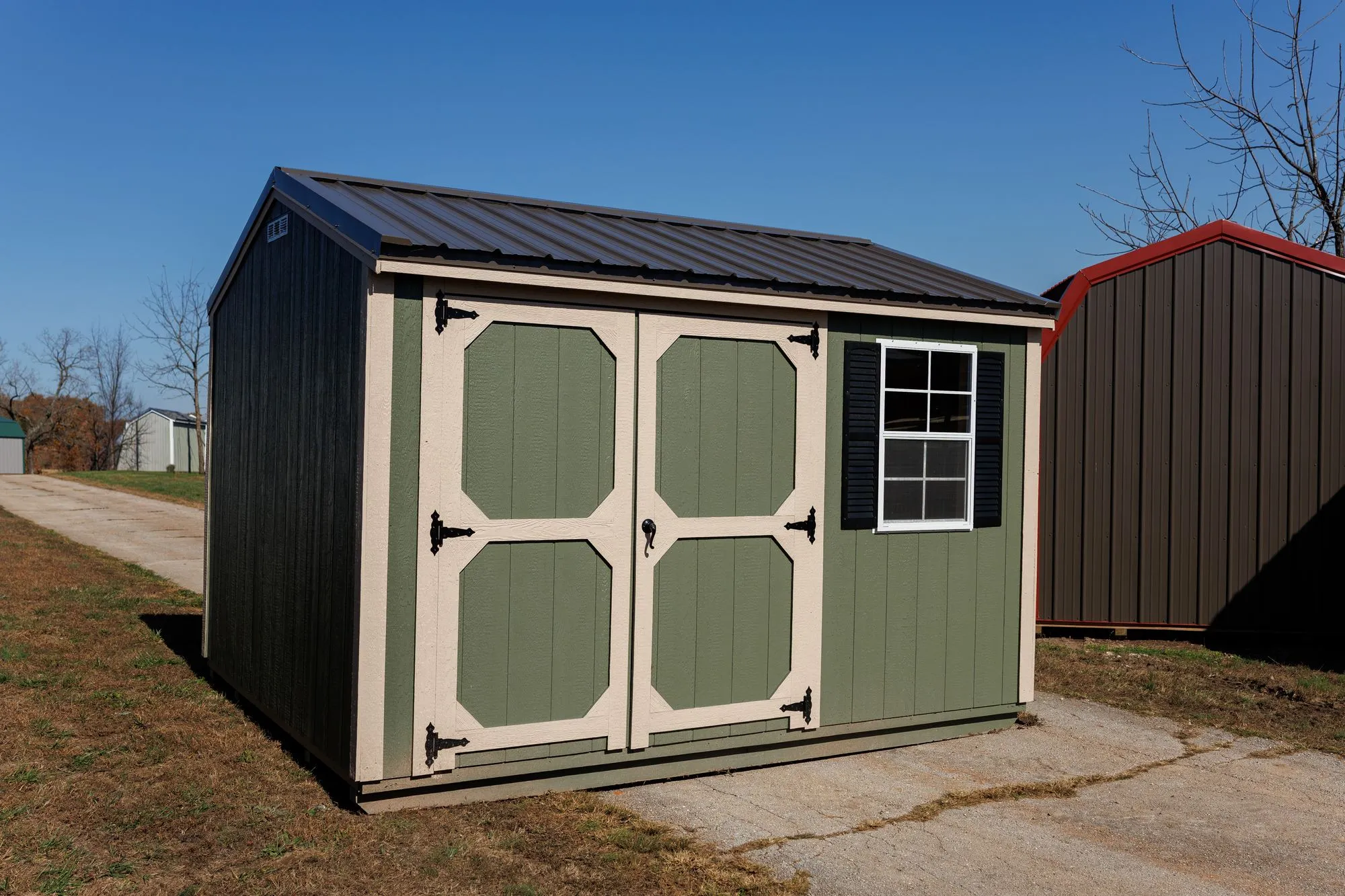 Garden Shed with sage siding, cream trim, black roof, cream-framed doors, on the Hawthorn lot in Rocky Comfort, Missouri