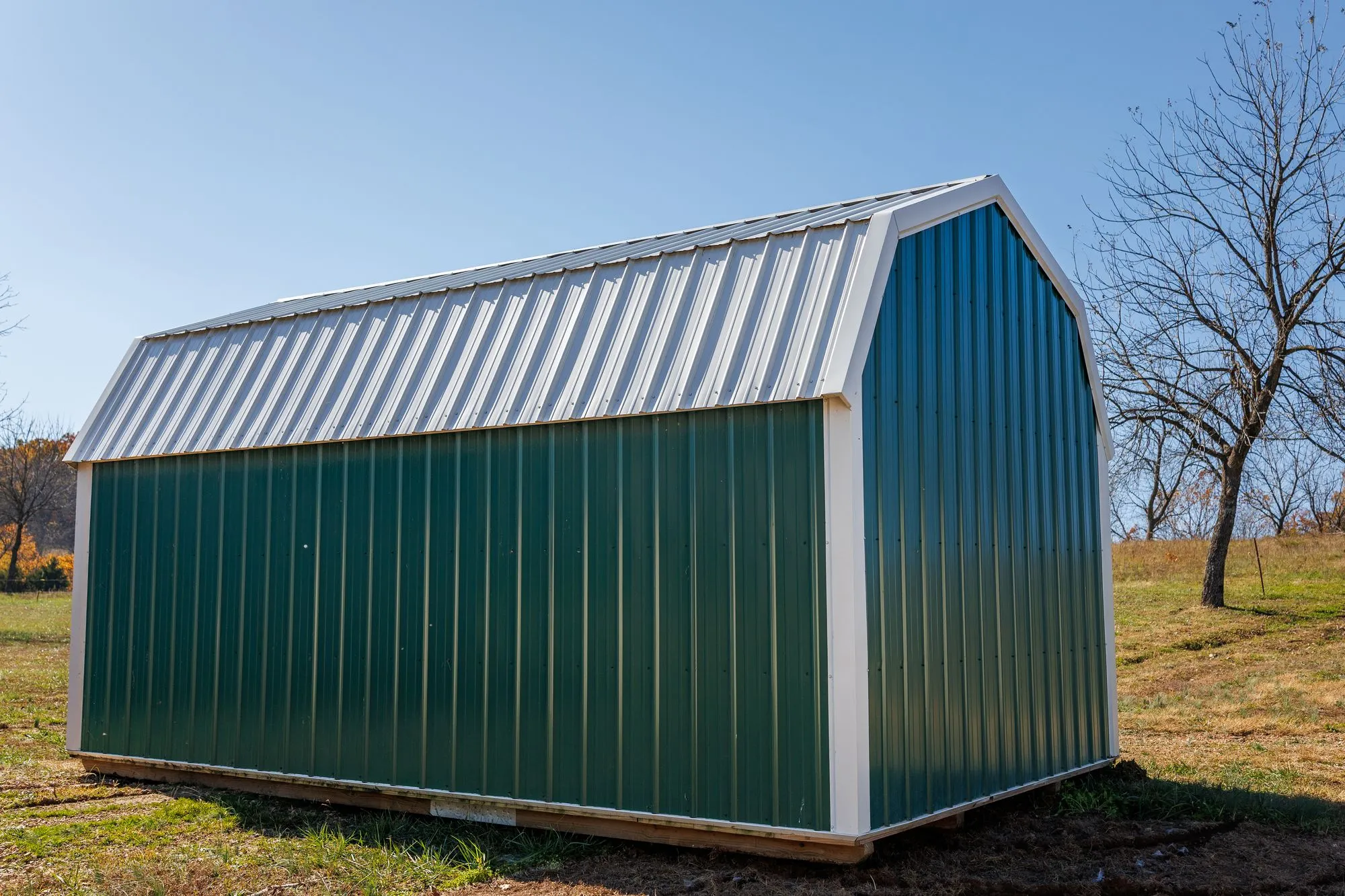 Lofted Barn with green metal siding with white trim, on the Hawthorn lot in Rocky Comfort, Missouri