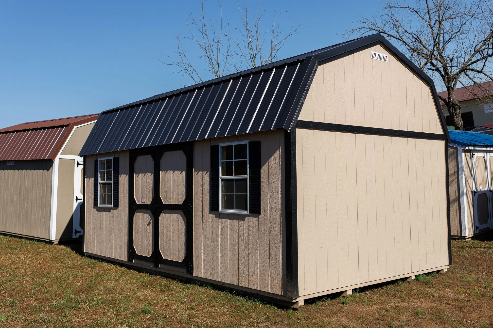 Lofted Garden Barn with tan siding, black trim and roof, octagon-panel doors, on the Hawthorn lot in Rocky Comfort, Missouri