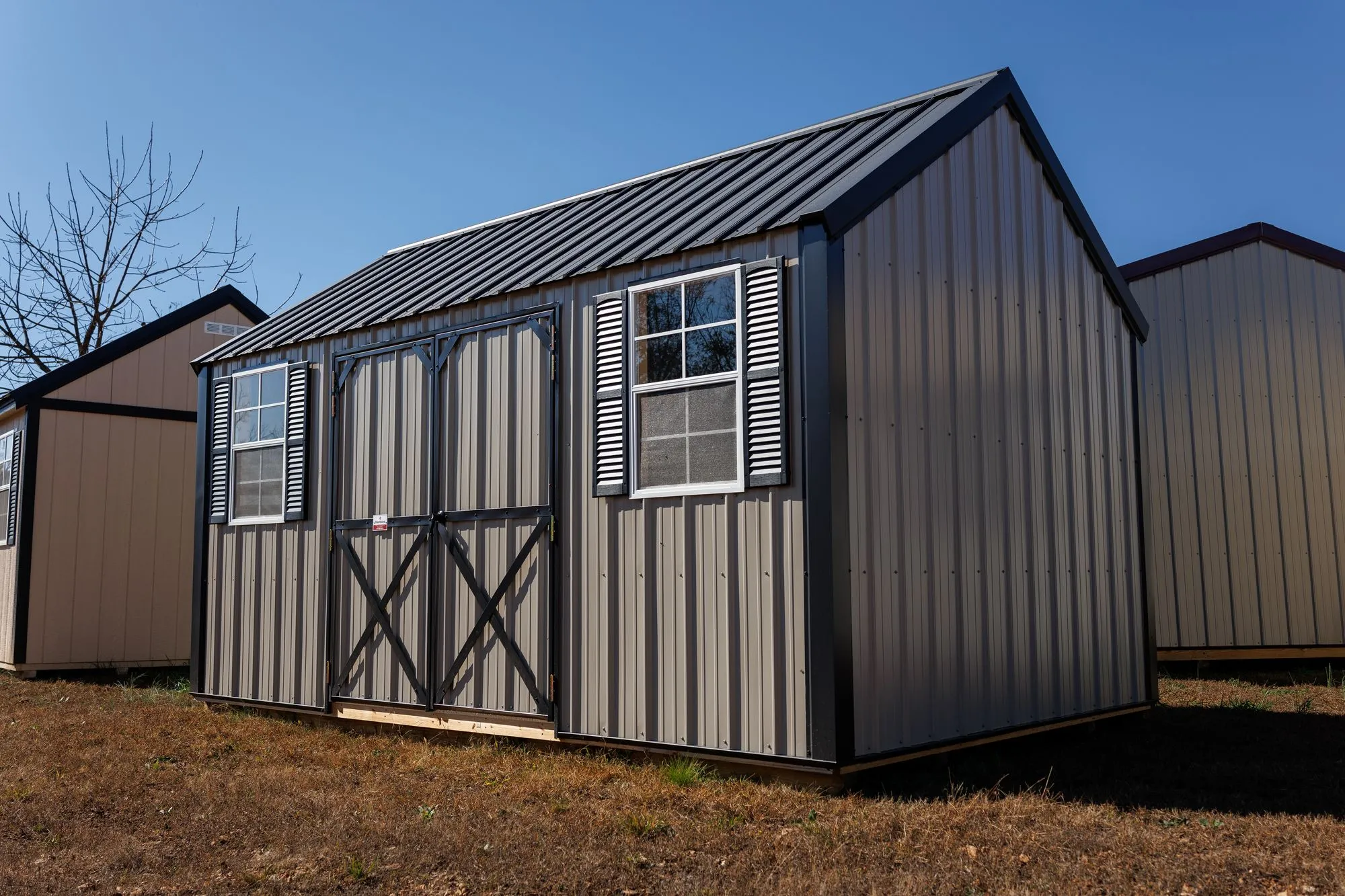 Lofted Garden Shed with clay metal siding, black trim and roof, black X-braced doors, two windows, on the Hawthorn lot in Rocky Comfort, Missouri
