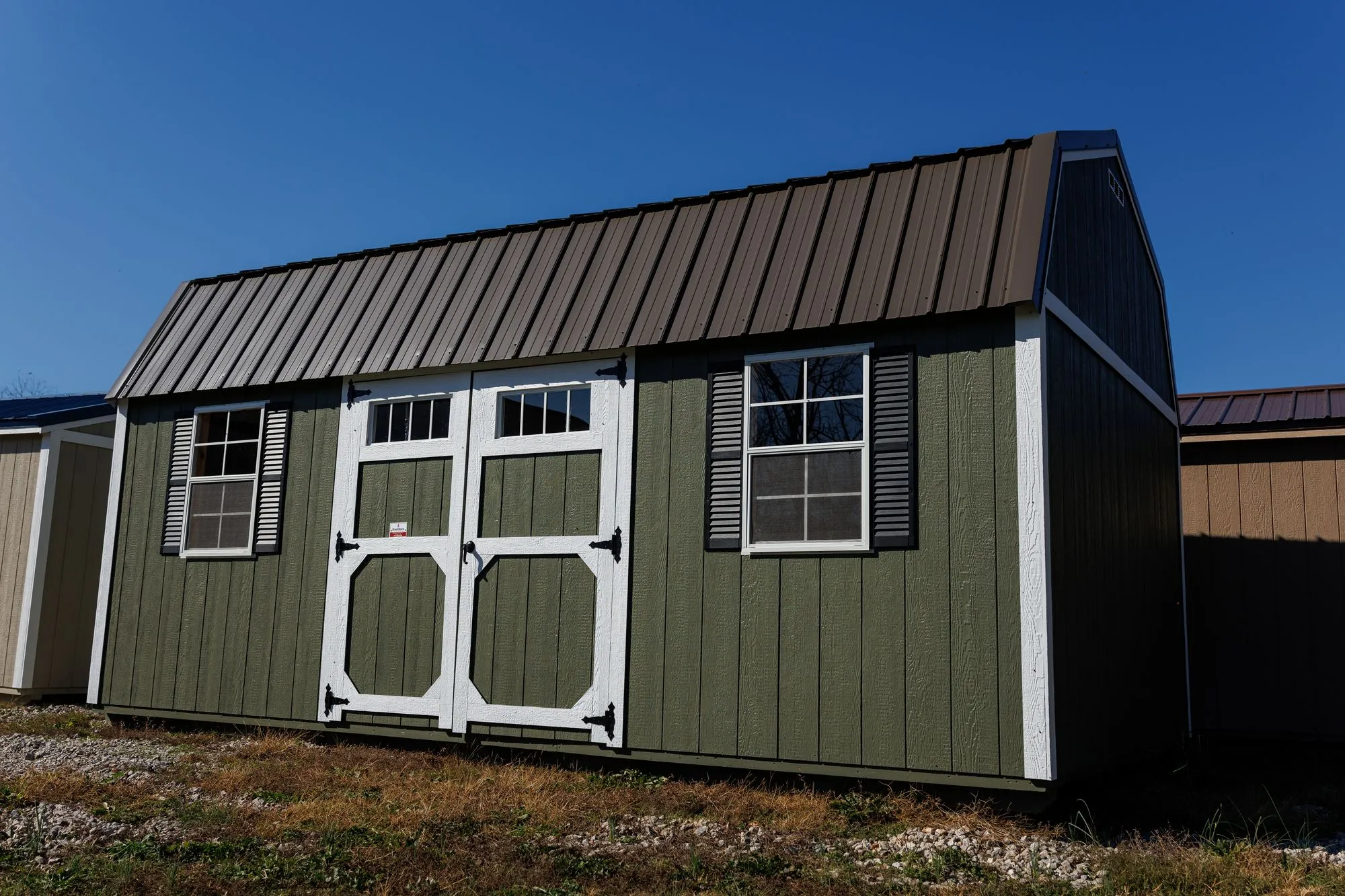 A green Hawthorn Lofted Garden Barn with white trim, a brown roof and white doors with transom windows