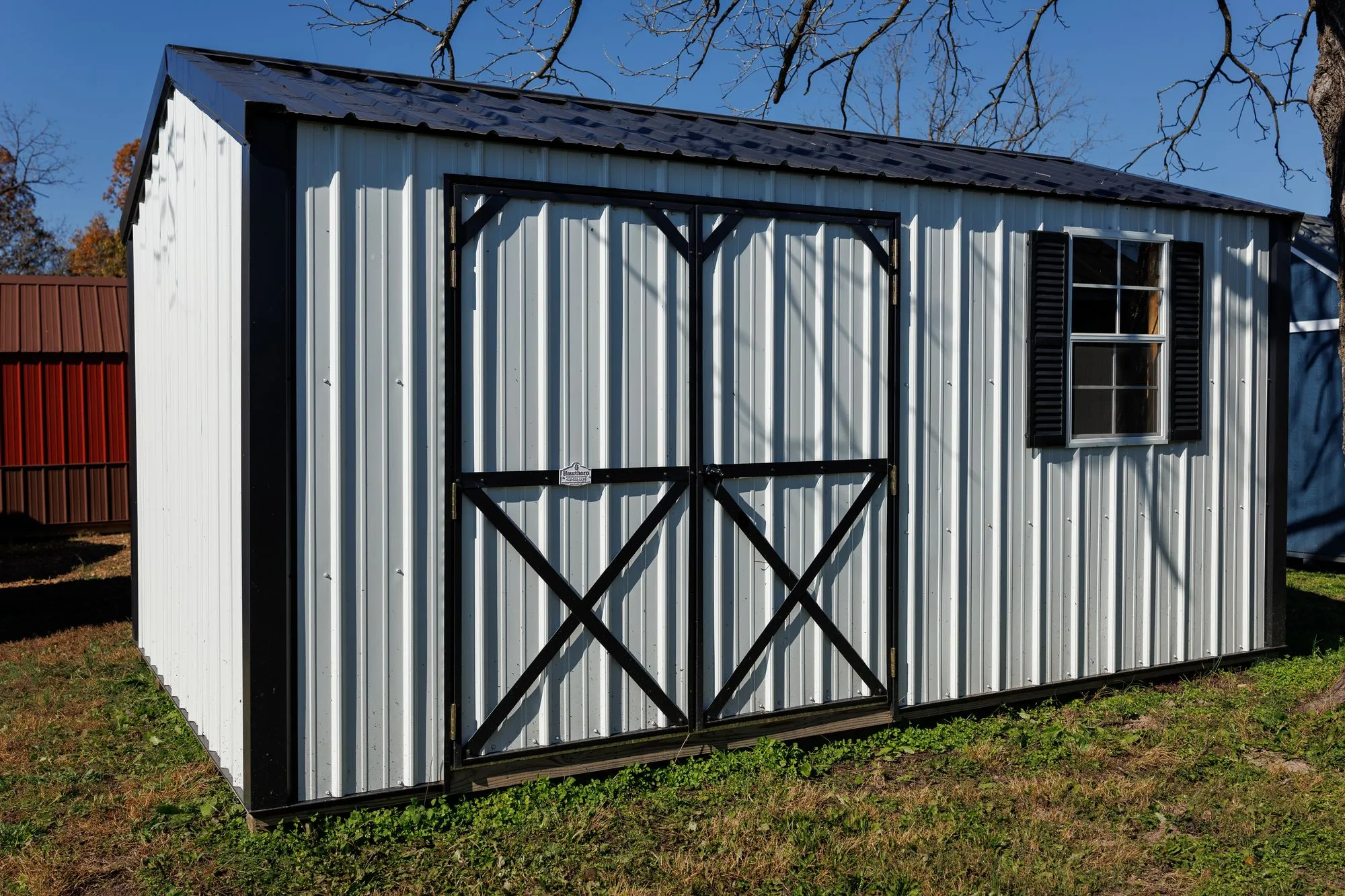 Garden Shed with white metal siding, black trim, black X-braced doors, on the Hawthorn lot in Rocky Comfort, Missouri
