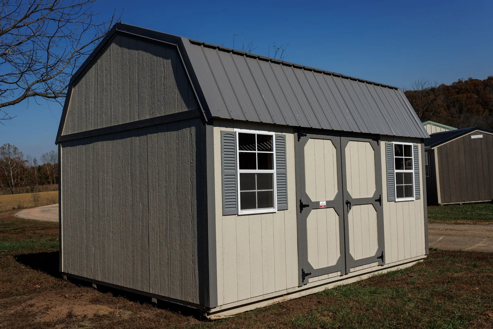 Lofted Garden Barn with cream and light-gray siding, charcoal trim, gray roof, on the Hawthorn lot in Rocky Comfort, Missouri
