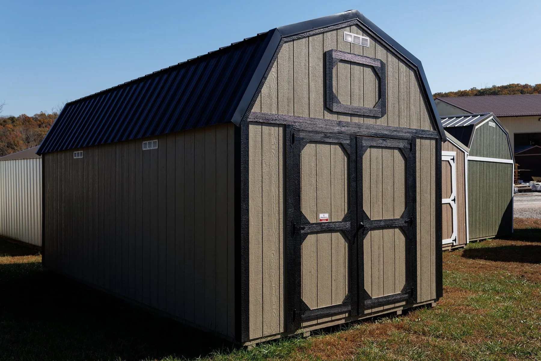 A Hawthorn lofted barn in tan LP SmartSide siding with black trim and black-framed doors